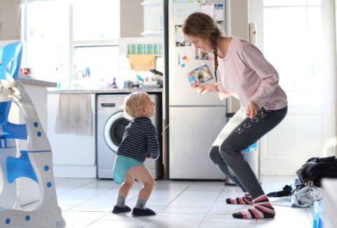 Madre bailando con su niño pequeño en la cocina de su casa